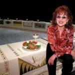 Retrato de Judy Chicago junto a su obra The dinner Party